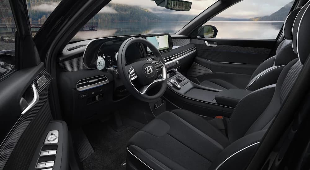 The black interior of a 2024 Hyundai Palisade is shown from the driver's side.