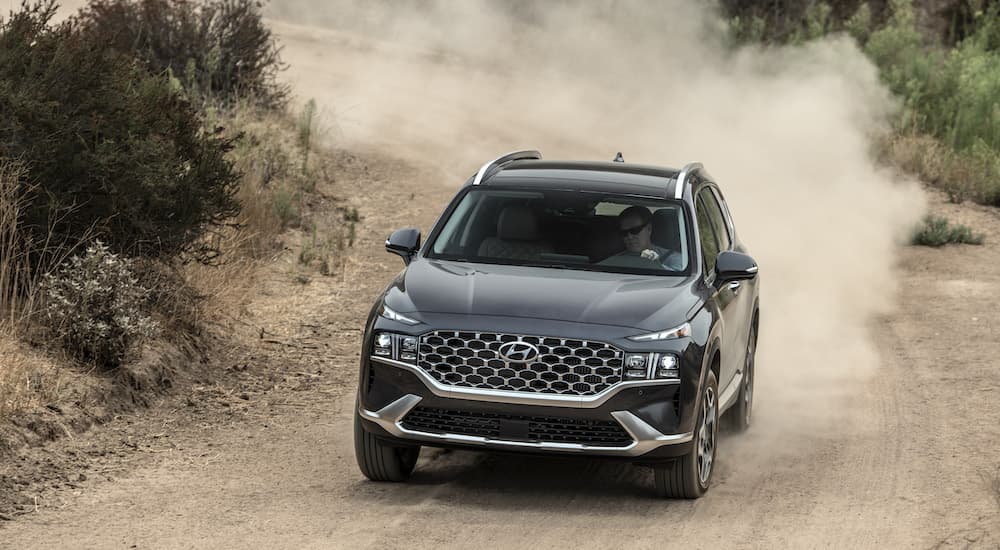A black 2022 Hyundai Santa Fe is shown driving off-road on a trail.