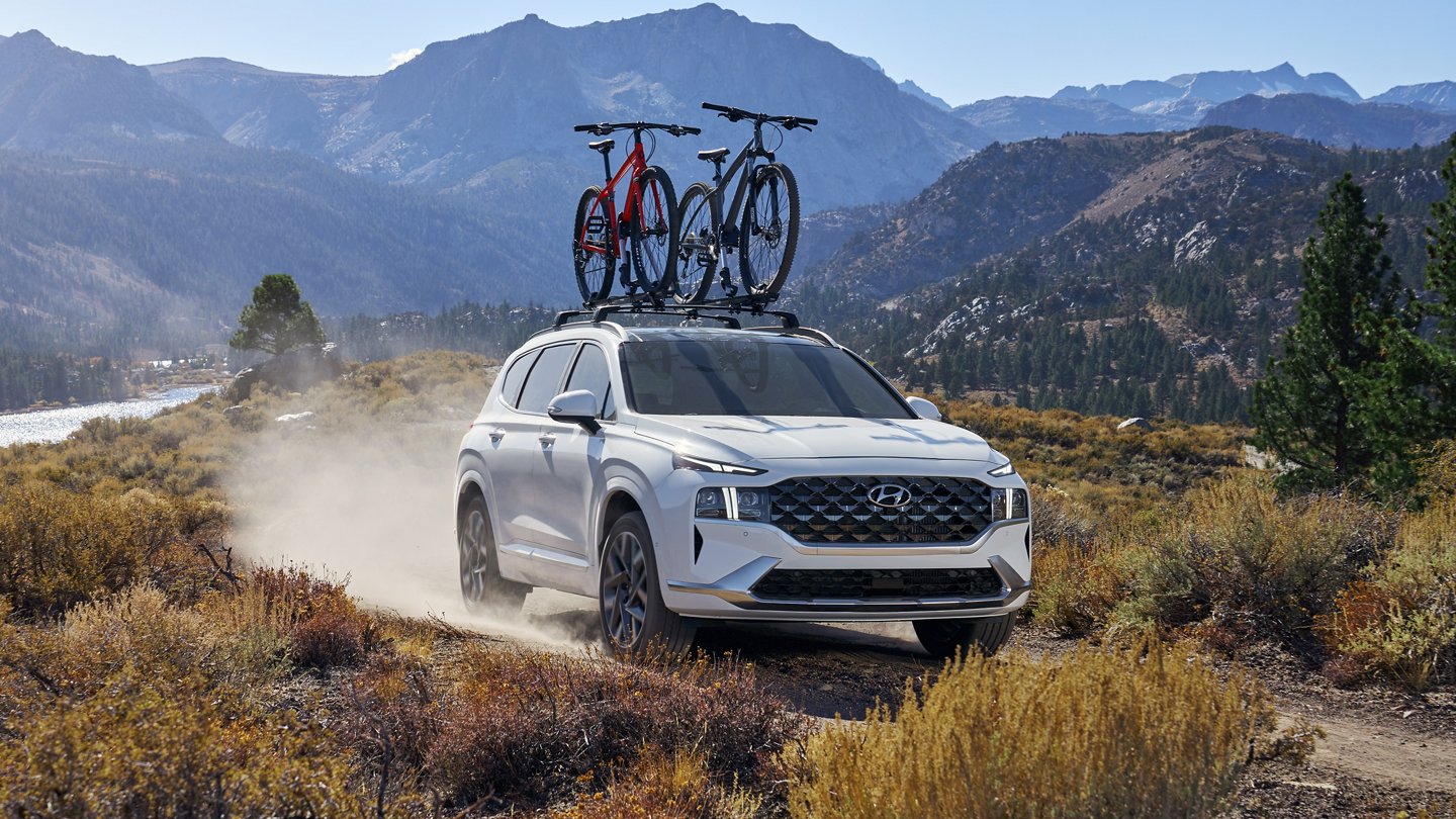 A white 2022 Hyundai Santa Fe is shown driving on a trail after visiting a used Hyundai dealer.