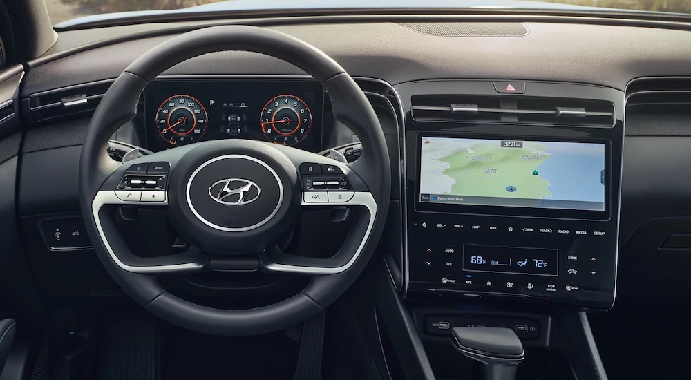 A steering wheel and dashboard in the black interior of a 2024 Hyundai Santa Cruz.