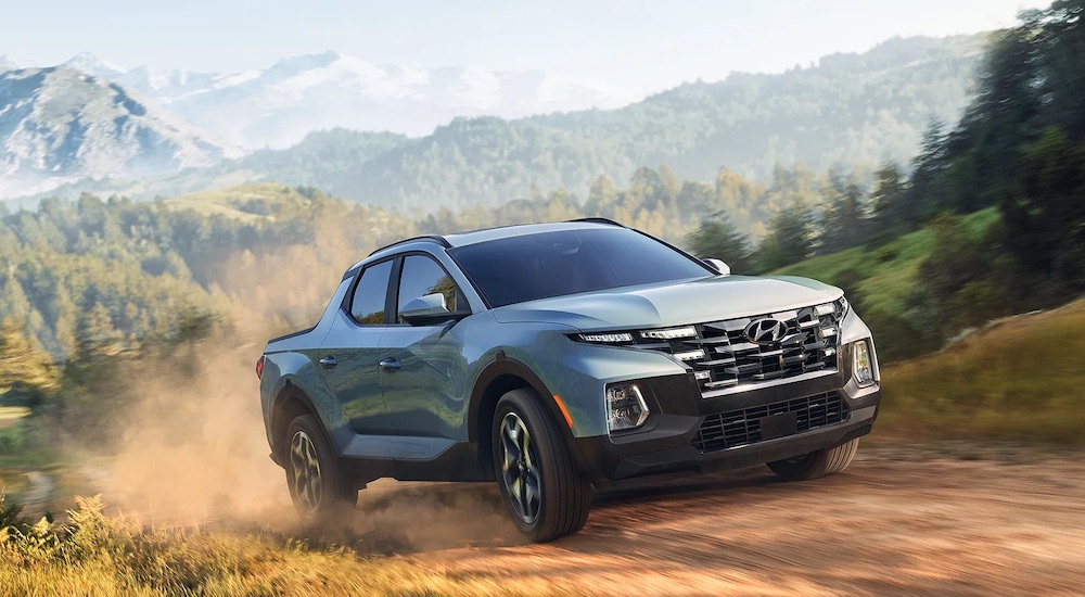 A blue 2025 Hyundai Santa Cruz driving on a dirt road from a Hyundai dealer in Knoxville.