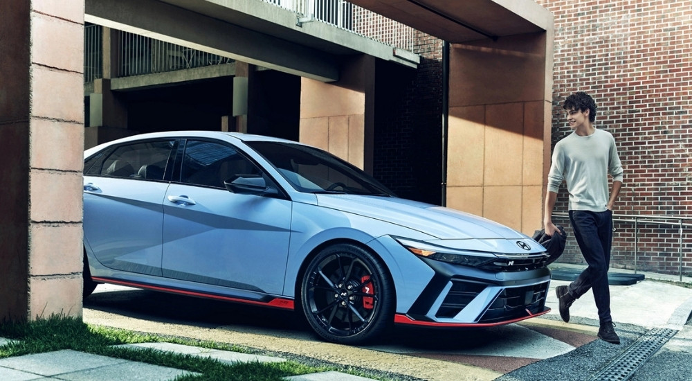 A light blue 2025 Hyundai Elantra N parked outside a brick building.