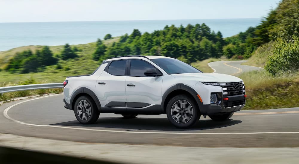 A white 2025 Santa Cruz XRT is driving on a winding road after visiting a Hyundai dealer near Norris.