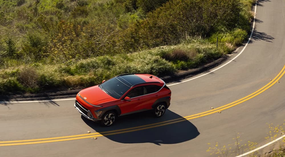 High angle view of a red 2025 Hyundai Kona driving around a bend.