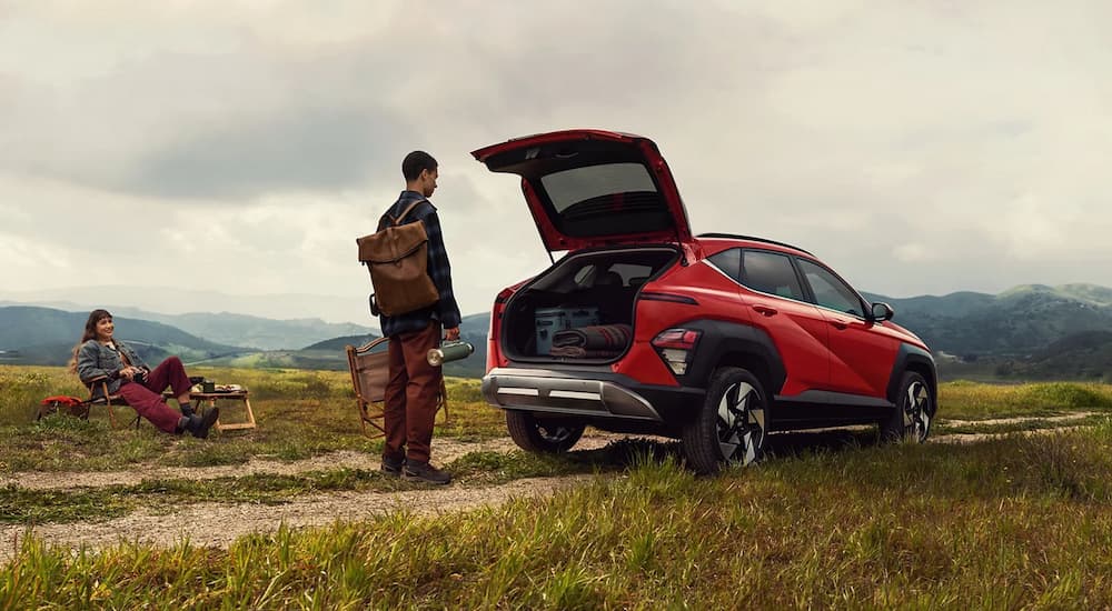 A man standing near a red 2025 Hyundai Kona with an open hatchback.