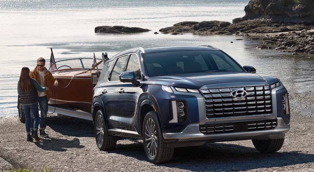Blue 2026 Hyundai Palisade towing a boat out of a lake.