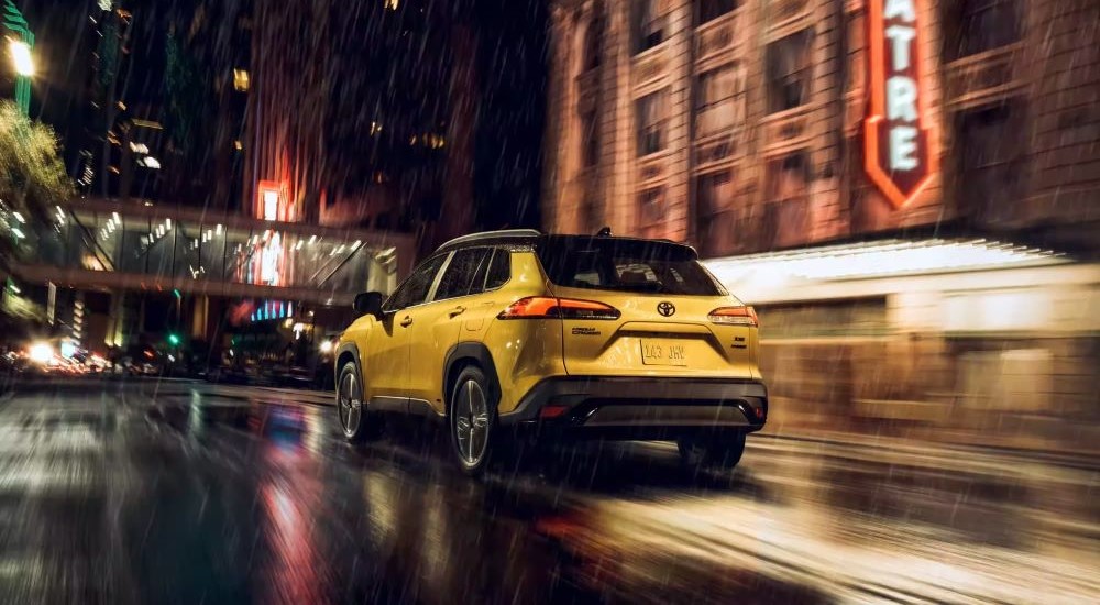 Yellow 2023 Toyota Corolla Cross driving on a city street at night