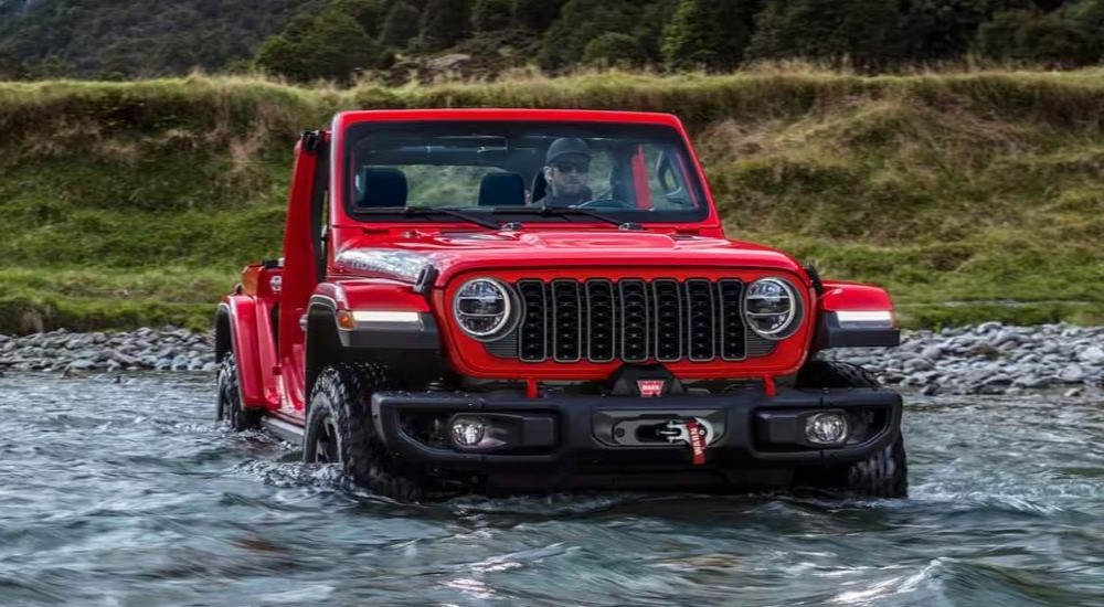 Red 2024 Jeep Wrangler Rubicon fording a river after visiting a dealer with used cars for sale in Knoxville.