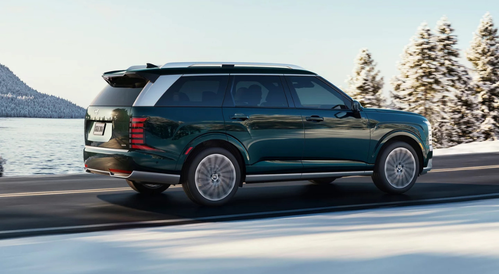 Green 2026 Hyundai Palisade driving on an empty road in winter