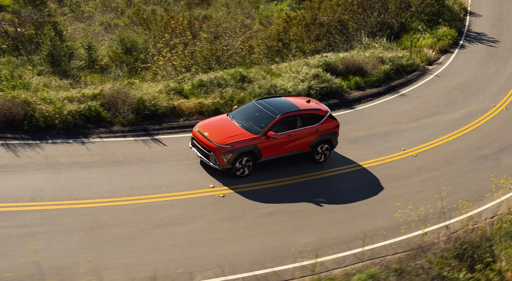 Orange 2026 Hyundai Kona driving on a winding road