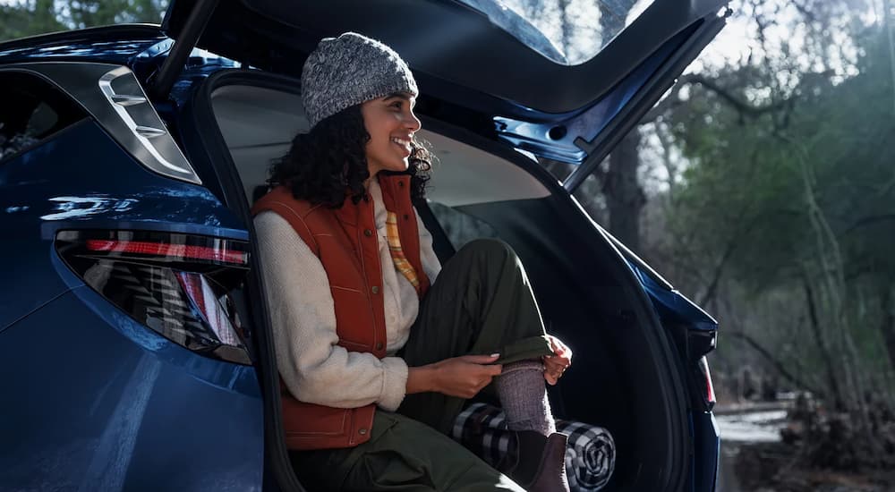 Woman sitting in the open trunk of a blue 2026 Hyundai Tucson