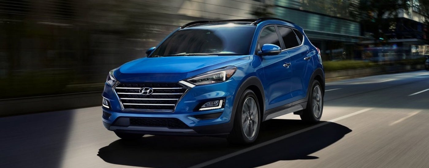 Blue 2021 Hyundai Tucson driving on a city street