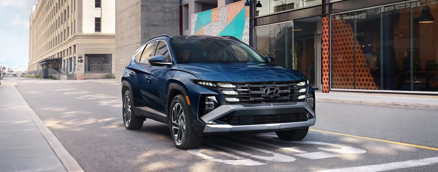 Blue 2026 Hyundai Tucson driving down a city street.