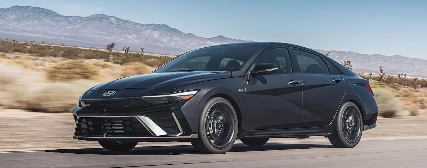 Black 2026 Hyundai Elantra driving down an open road.