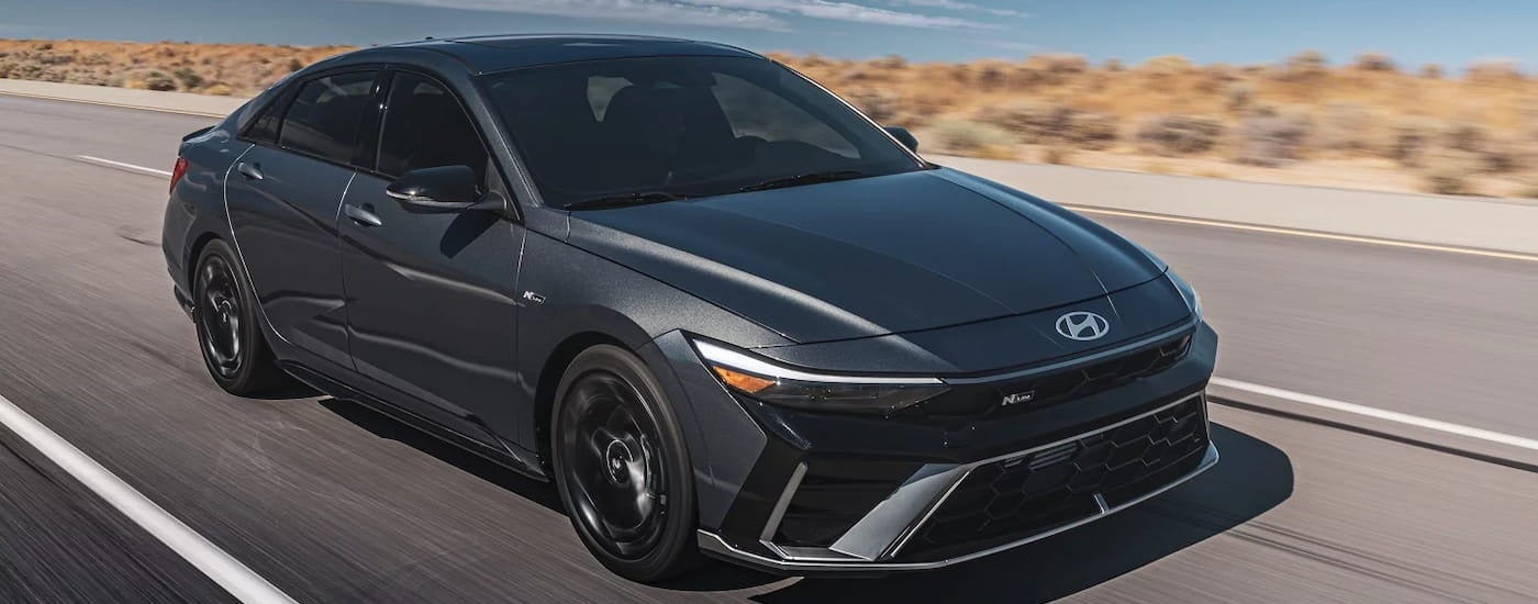 Black 2026 Hyundai Elantra driving down an open road.