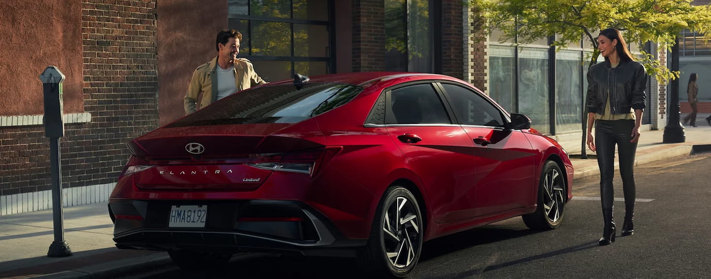 Rear of a red 2026 Hyundai Elantra parked by a curb.