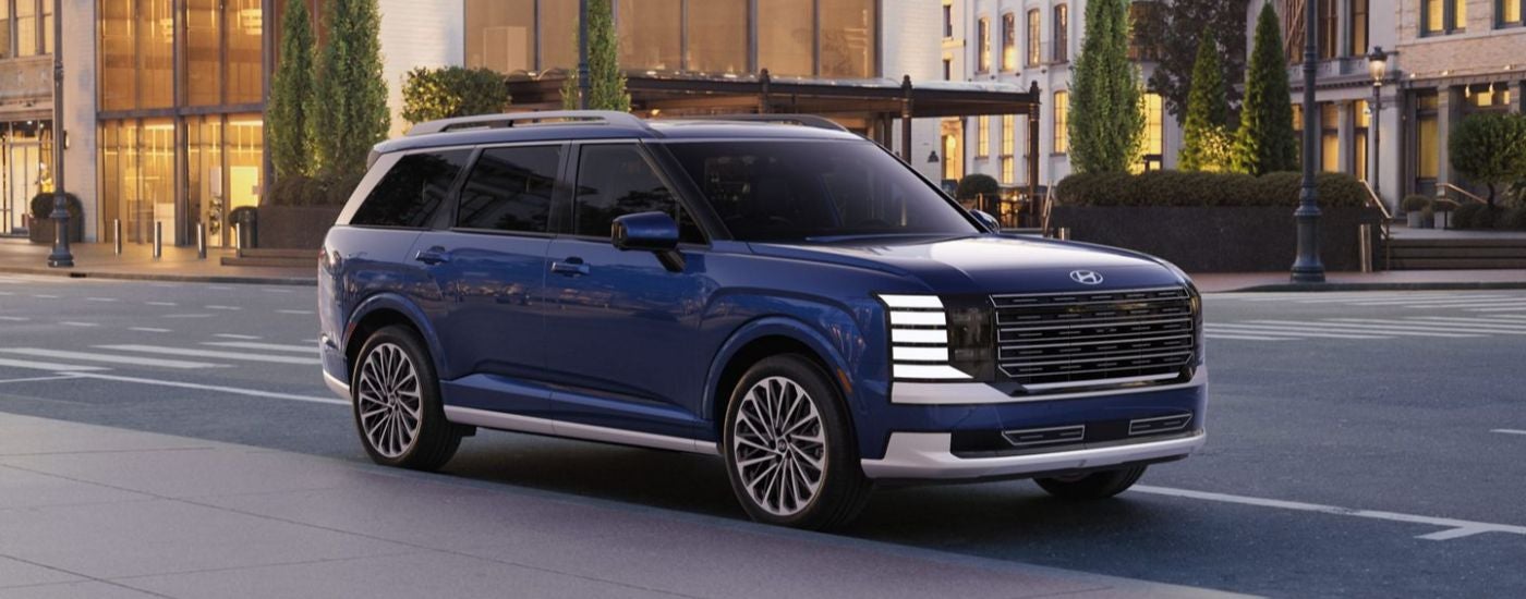 A blue 2027 Hyundai Palisade Hybrid parked on a city street.
