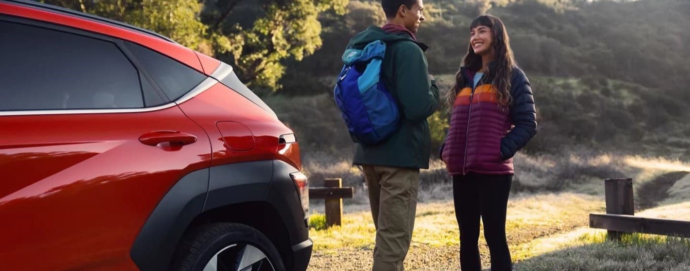 Hikers are shown next to a red 2024 Hyundai Kona Limited.