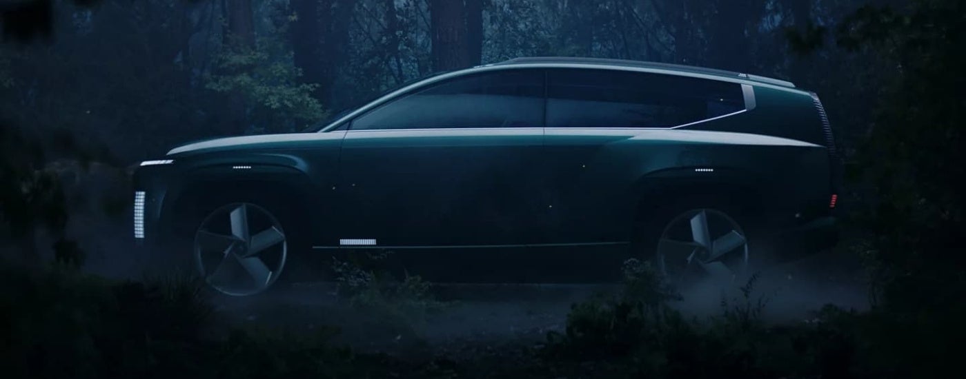 A grey 2024 Hyundai IONIQ 7 is in a forest at night.