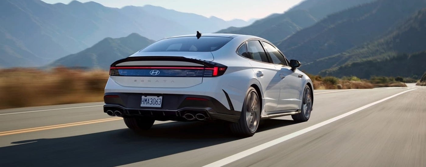 A white 2024 Hyundai Sonata N-Line is driving to a Hyundai dealer near Kingston.