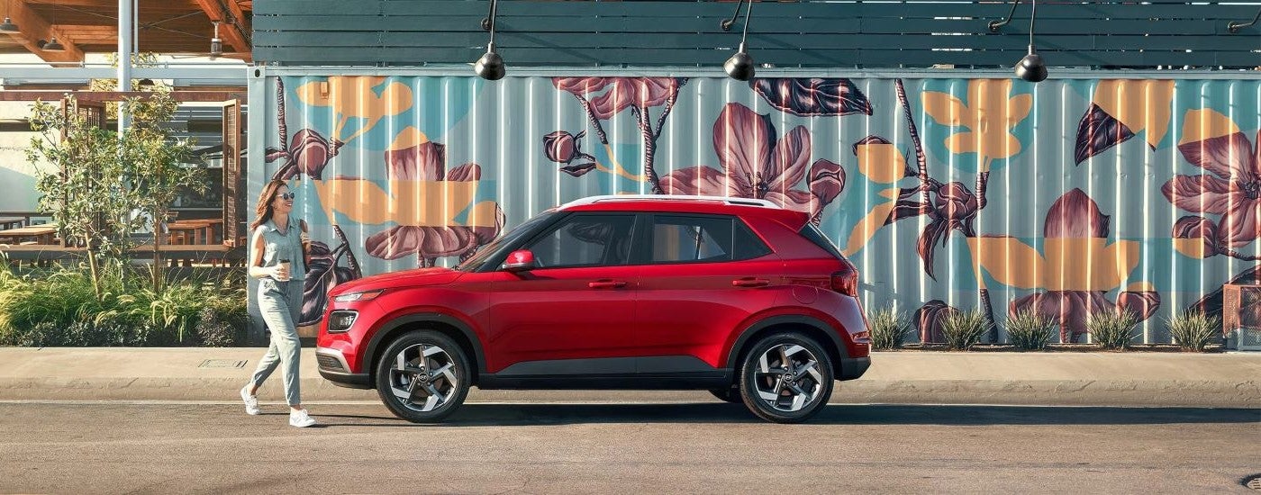 Side angle view of a red 2023 Hyundai Venue Limited parked by a wall.