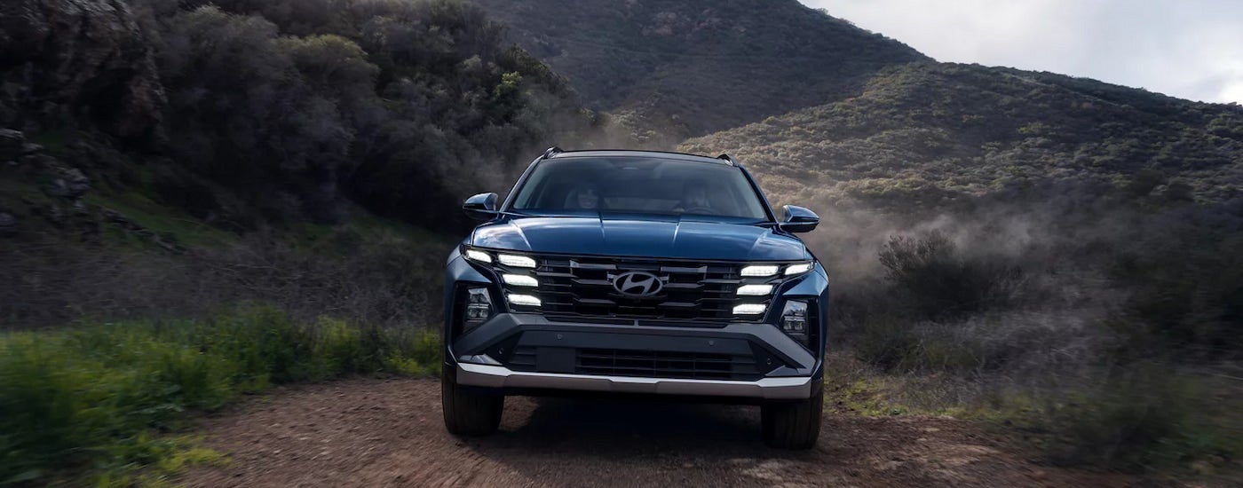 Head-on view of a black 2025 Hyundai Tucson Limited driving on a hilly dirt trail.