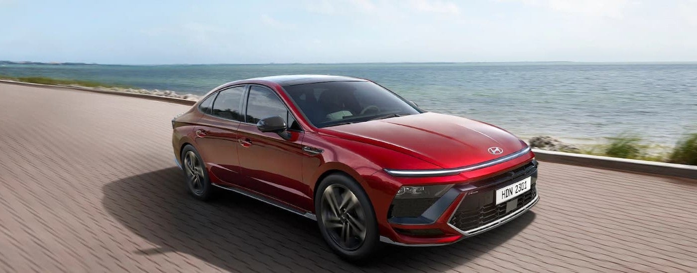 A red 2024 Hyundai Sonata driving by an ocean.